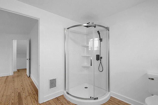 bathroom featuring wood-type flooring, an enclosed shower, and toilet