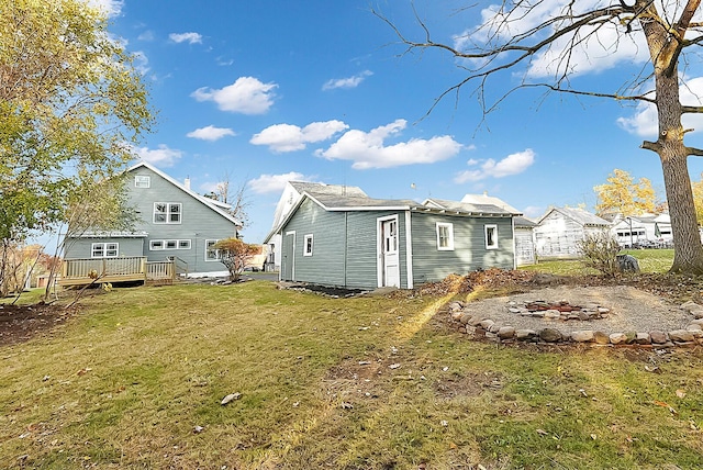 rear view of house with a wooden deck, a yard, and a fire pit