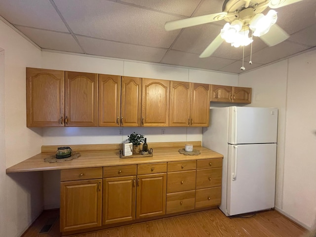 kitchen featuring a paneled ceiling, ceiling fan, white refrigerator, and light hardwood / wood-style flooring