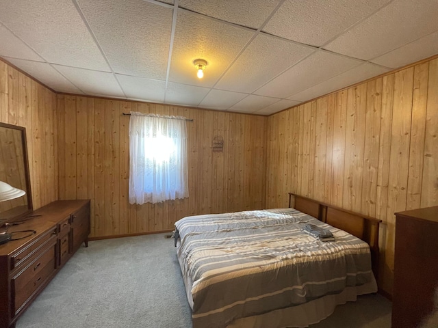 bedroom featuring a drop ceiling, wood walls, and carpet floors