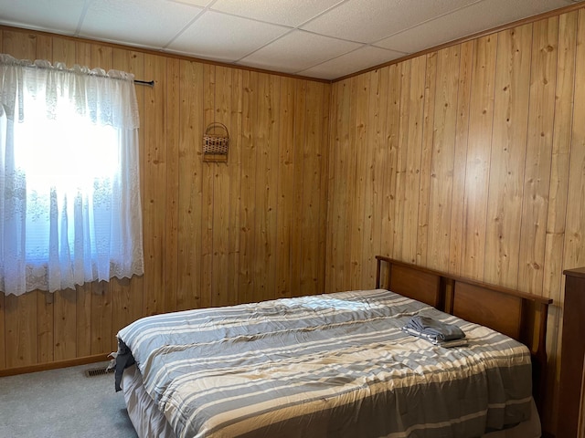 bedroom featuring carpet flooring, a paneled ceiling, and wooden walls