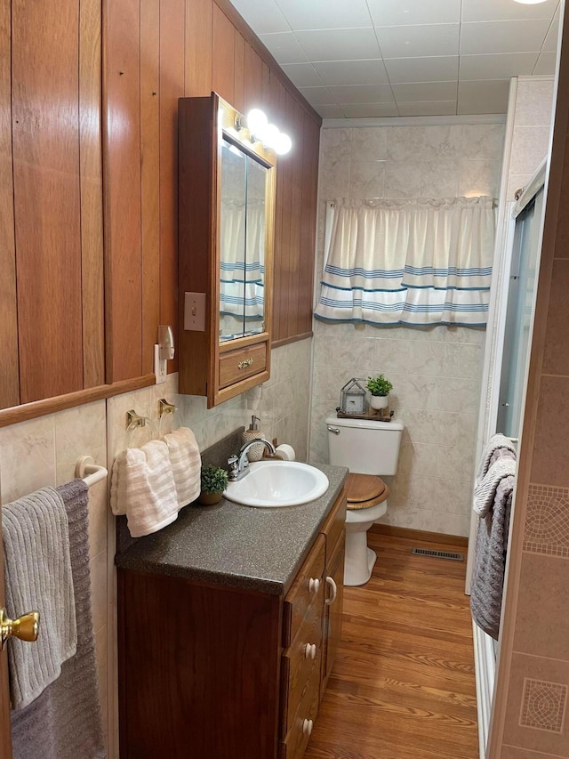 bathroom with hardwood / wood-style floors, vanity, toilet, and a shower with shower door