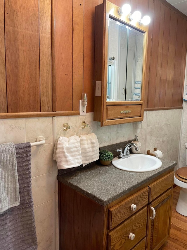 bathroom with hardwood / wood-style floors, vanity, toilet, and tile walls