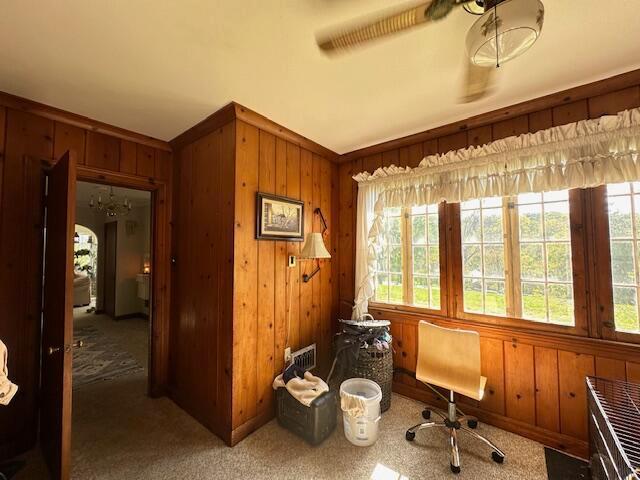 home office with ceiling fan, carpet floors, and wooden walls