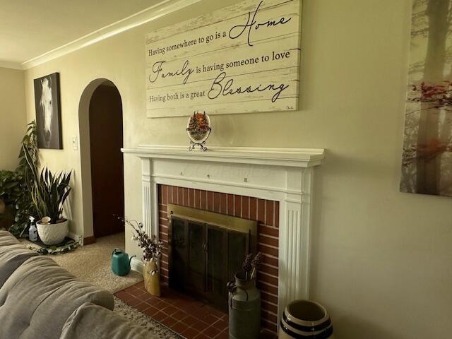 living room with carpet, crown molding, and a fireplace