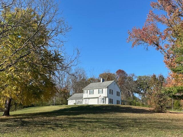 view of side of home featuring a chimney and a yard