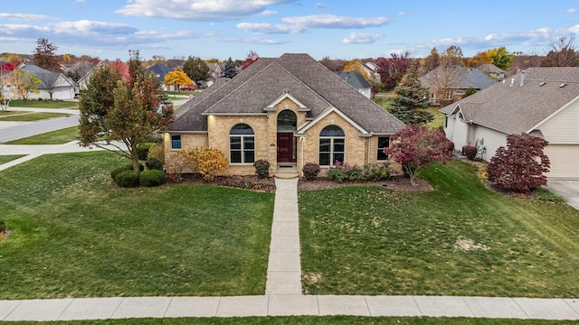 view of front of property featuring roof with shingles, a front yard, and brick siding