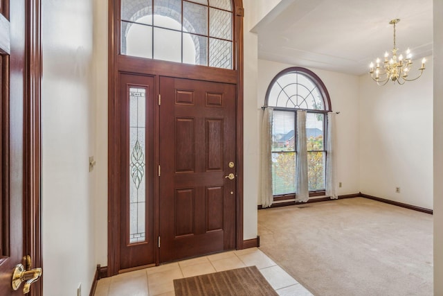 entrance foyer with a high ceiling, light colored carpet, a healthy amount of sunlight, and a notable chandelier