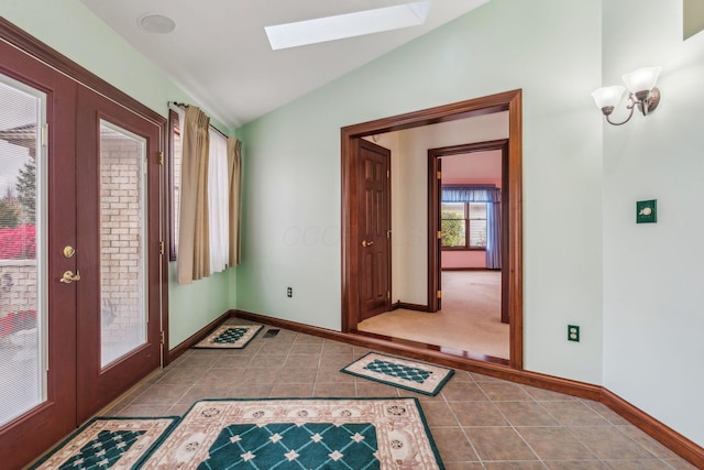 interior space featuring light tile patterned flooring, french doors, and vaulted ceiling with skylight