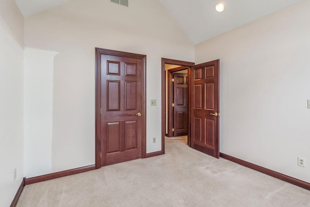 unfurnished bedroom featuring light colored carpet and vaulted ceiling