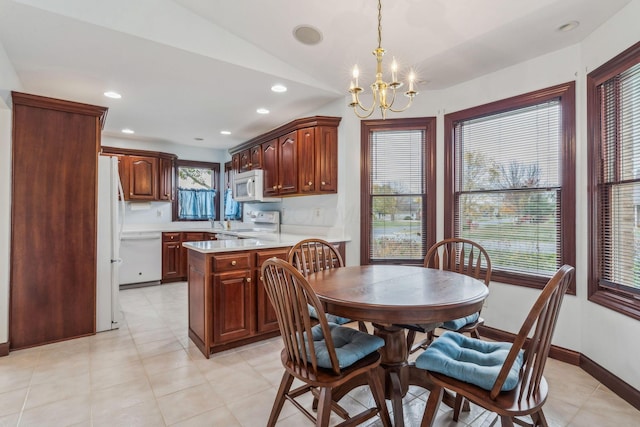 tiled dining space featuring a healthy amount of sunlight, vaulted ceiling, and a notable chandelier