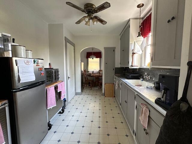 kitchen with backsplash, sink, ceiling fan, stainless steel fridge, and gray cabinets