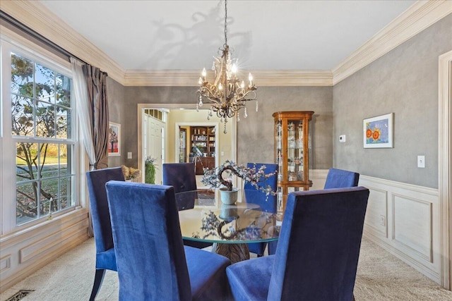 dining area featuring light colored carpet, ornamental molding, and a notable chandelier