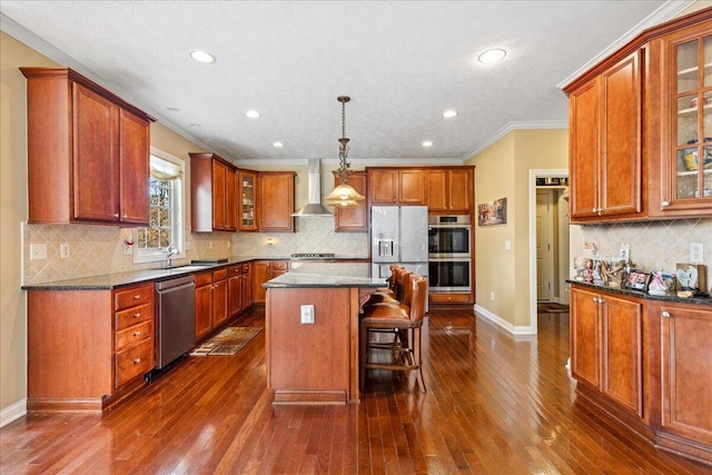 kitchen with a center island, hanging light fixtures, wall chimney exhaust hood, dark hardwood / wood-style flooring, and stainless steel appliances