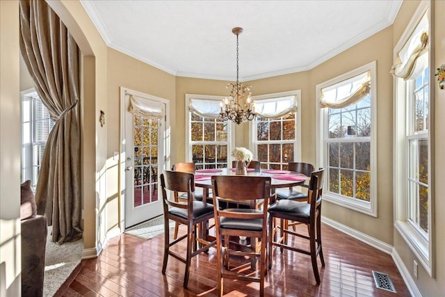 dining space featuring dark hardwood / wood-style floors, an inviting chandelier, and crown molding