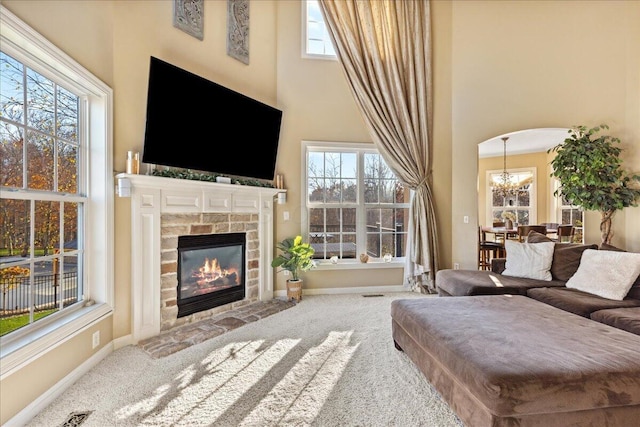 living room featuring a healthy amount of sunlight, carpet floors, a fireplace, and an inviting chandelier