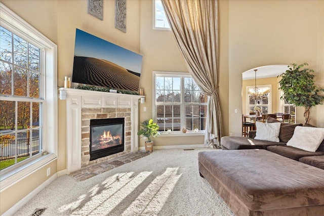 living room featuring carpet flooring, an inviting chandelier, a wealth of natural light, and a tiled fireplace