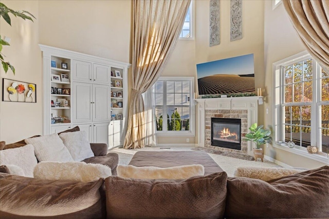 living room with built in shelves, a towering ceiling, and a brick fireplace