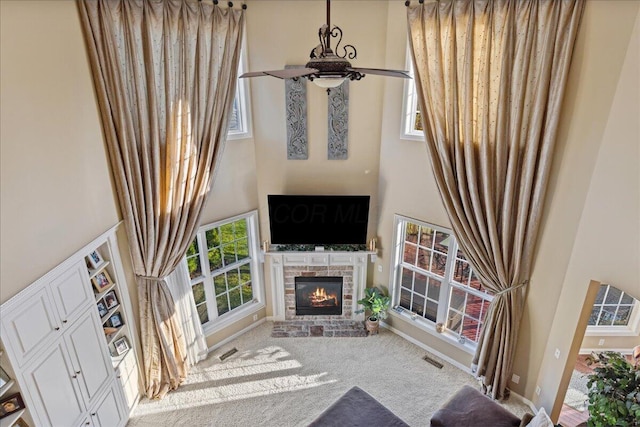 living room with a wealth of natural light, ceiling fan, a fireplace, and carpet floors