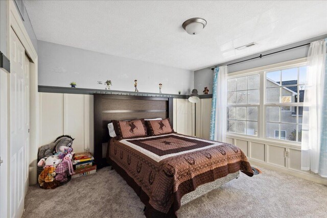 carpeted bedroom featuring a textured ceiling and a closet