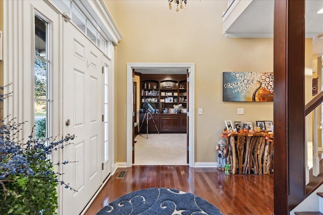 foyer entrance with dark wood-type flooring and ornamental molding