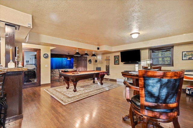 playroom with bar, wood-type flooring, a textured ceiling, and pool table