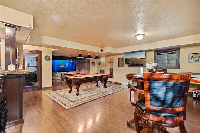 playroom featuring bar area, wood-type flooring, a textured ceiling, and pool table