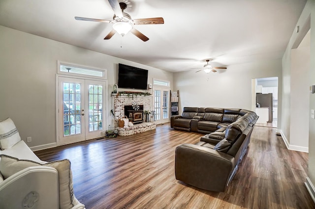 living room featuring a wood stove, ceiling fan, french doors, and hardwood / wood-style floors