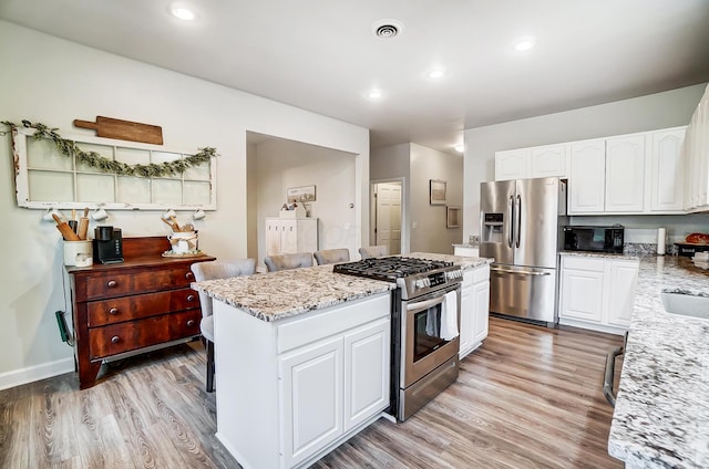 kitchen with white cabinets, stainless steel appliances, and light hardwood / wood-style floors