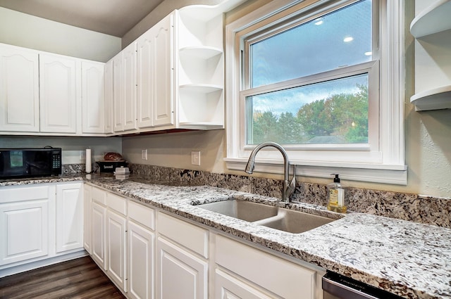 kitchen featuring light stone countertops, stainless steel dishwasher, dark wood-type flooring, sink, and white cabinets