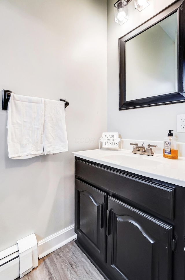 bathroom featuring hardwood / wood-style floors, vanity, and a baseboard heating unit