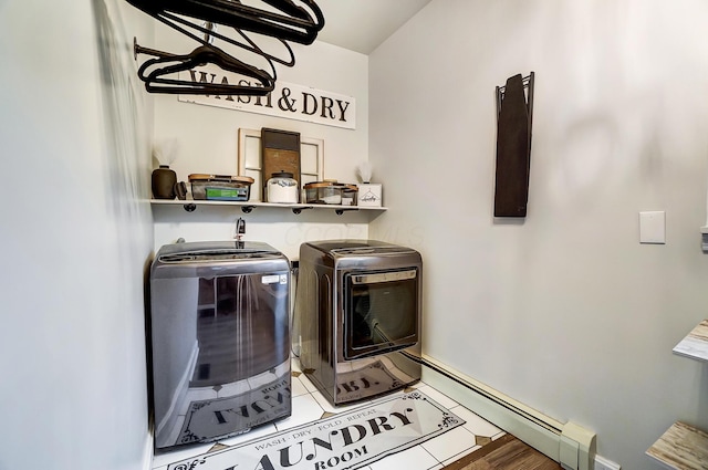 clothes washing area with hardwood / wood-style flooring, a baseboard heating unit, and washing machine and clothes dryer