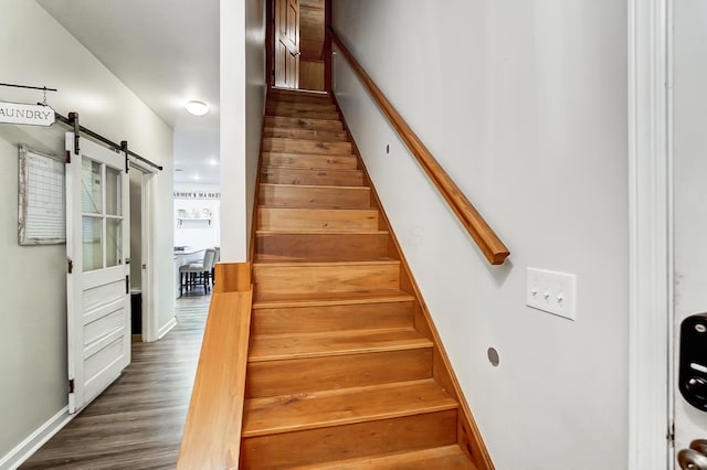 stairway with a barn door and hardwood / wood-style floors