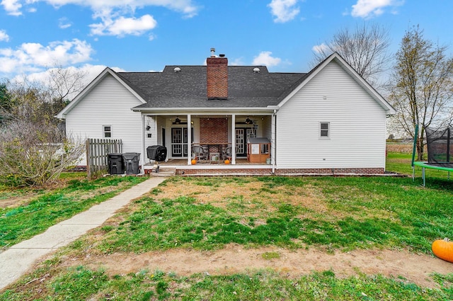 rear view of property featuring a yard, a trampoline, ceiling fan, and a patio area