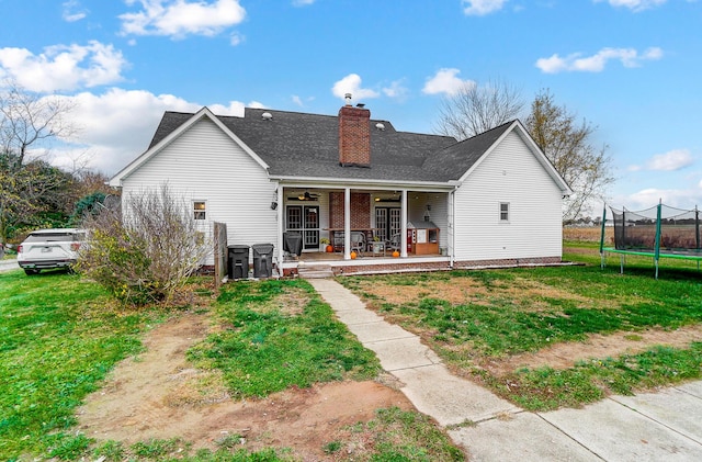 back of property with a patio, a trampoline, ceiling fan, and a lawn