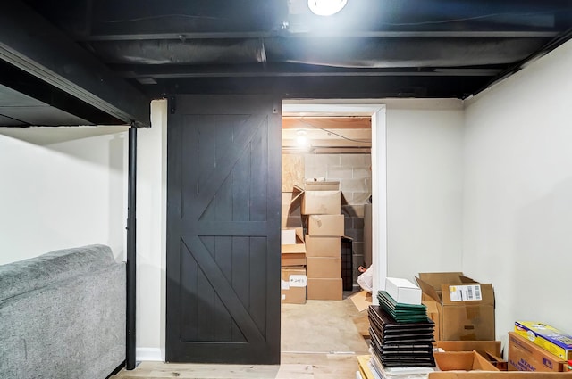 basement with wood-type flooring and a barn door