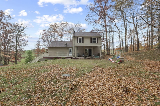 back of property featuring a yard and a playground