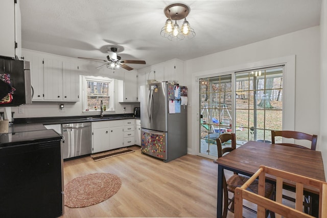 kitchen with stainless steel appliances, white cabinetry, sink, and light wood-type flooring