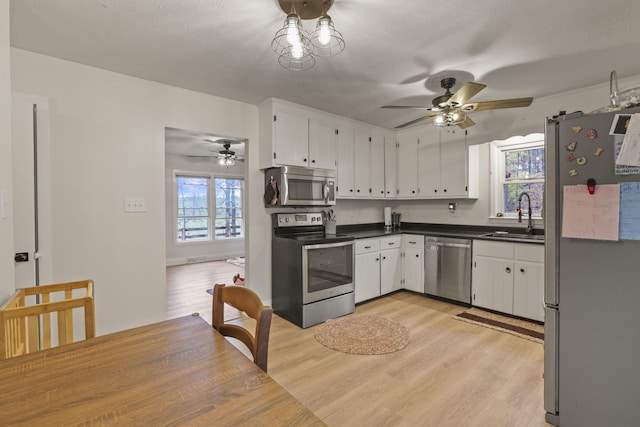 kitchen featuring white cabinetry, sink, light hardwood / wood-style floors, and appliances with stainless steel finishes