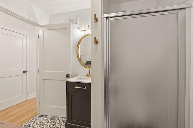 bathroom featuring vanity, hardwood / wood-style floors, and a shower with door