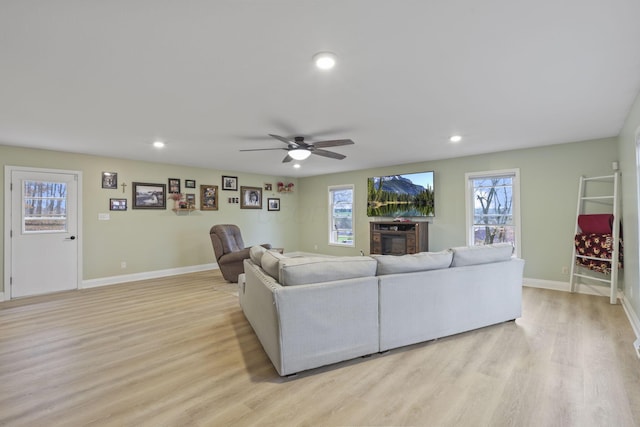 living room with ceiling fan, plenty of natural light, a fireplace, and light hardwood / wood-style floors