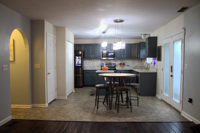 kitchen with backsplash, gray cabinets, dark hardwood / wood-style floors, and appliances with stainless steel finishes