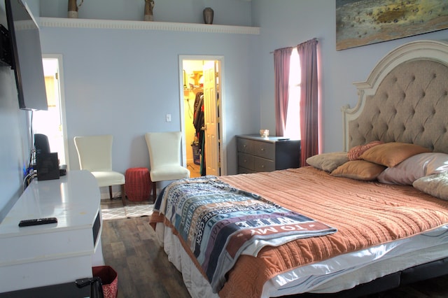 bedroom featuring dark hardwood / wood-style flooring, a walk in closet, multiple windows, and a closet