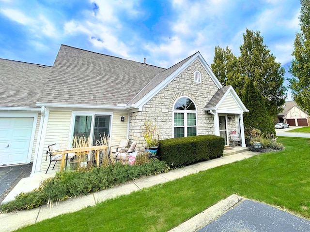 view of front of house with a garage, stone siding, a front lawn, and roof with shingles