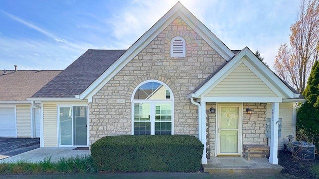 7837 Farmsbury Dr, Reynoldsburg, OH 43068 - view of front of house featuring a shingled roof, stone siding, and a garage