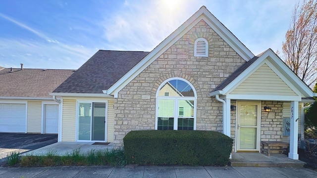 7837 Farmsbury Dr, Reynoldsburg, OH 43068 - view of front facade with roof with shingles, an attached garage, driveway, and stone siding