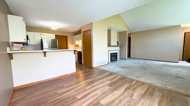 7837 Farmsbury Dr, Reynoldsburg, OH 43068 - kitchen with visible vents, light wood-type flooring, light countertops, freestanding refrigerator, and a peninsula
