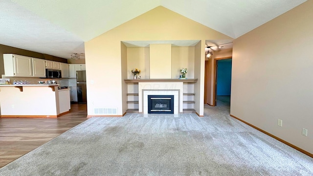 7837 Farmsbury Dr, Reynoldsburg, OH 43068 - unfurnished living room featuring light colored carpet, a tiled fireplace, visible vents, vaulted ceiling, and baseboards