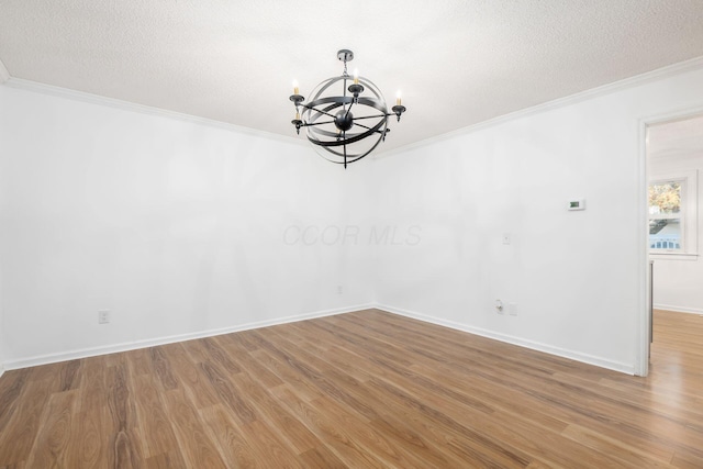 spare room featuring crown molding, hardwood / wood-style floors, a chandelier, and a textured ceiling