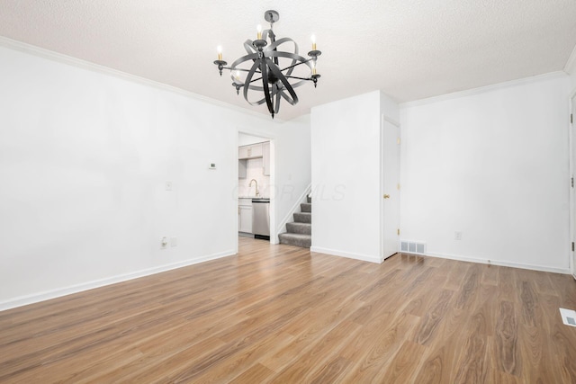 interior space featuring sink, ornamental molding, a textured ceiling, light hardwood / wood-style floors, and a chandelier